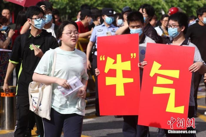 6月7日，江苏省南京市雨花台中学高考考点前，高二的学生手举“牛气冲天”“牛转乾坤”字样为考生加油鼓劲。当日，2021年中国高考拉开大幕，1078万考生赶赴考场。 中新社记者 泱波 摄