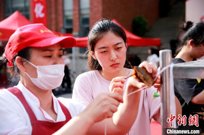 集大学生在食堂师傅指导下感受包粽子的魅力。　刘金昆 摄